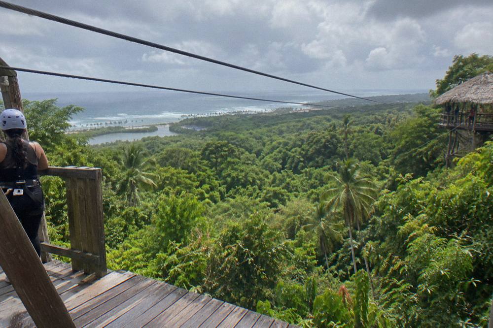 Rain clouds moving over a green jungle canopy with zipline cables strung between platforms